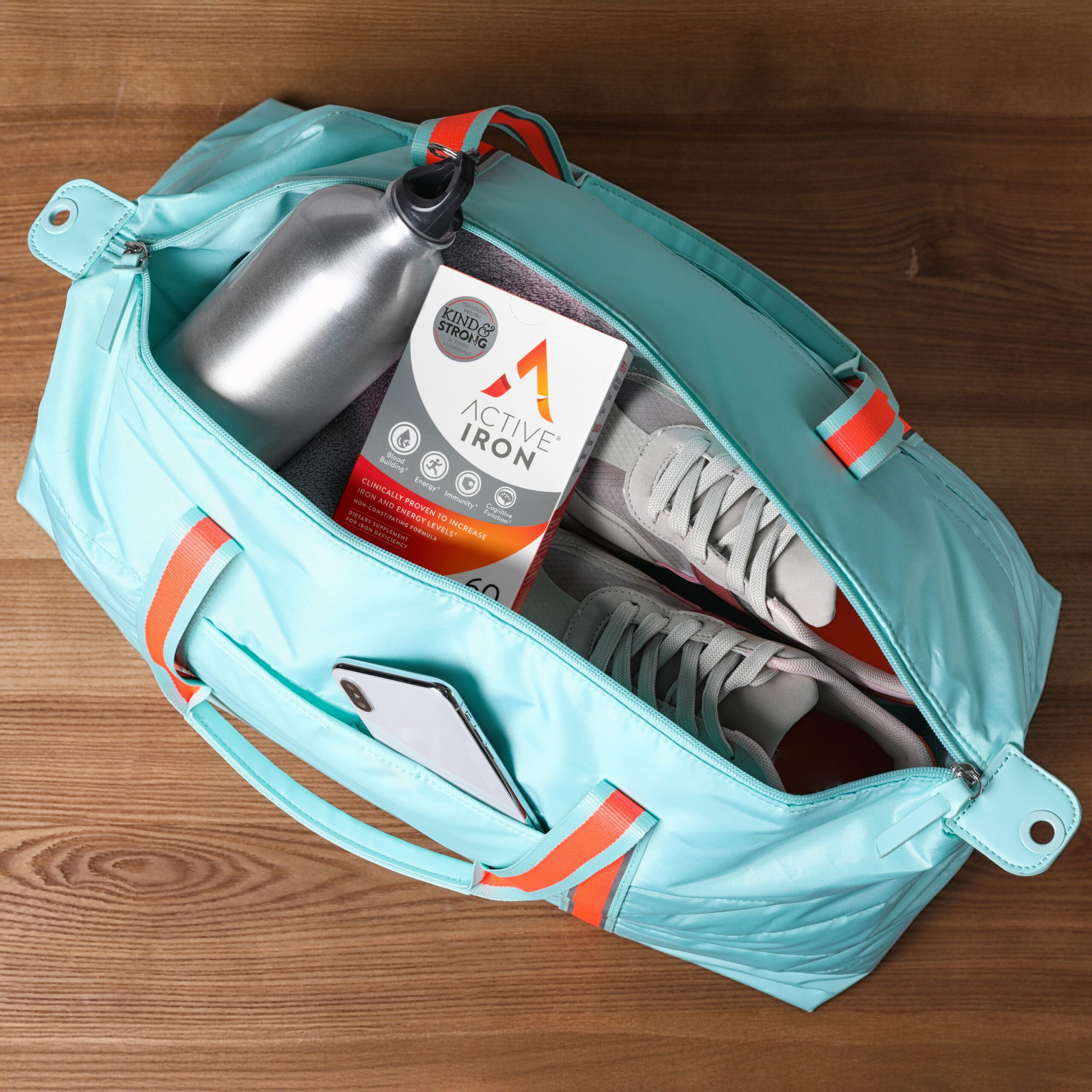 Open sports bag full of gym stuff on wooden background, top view