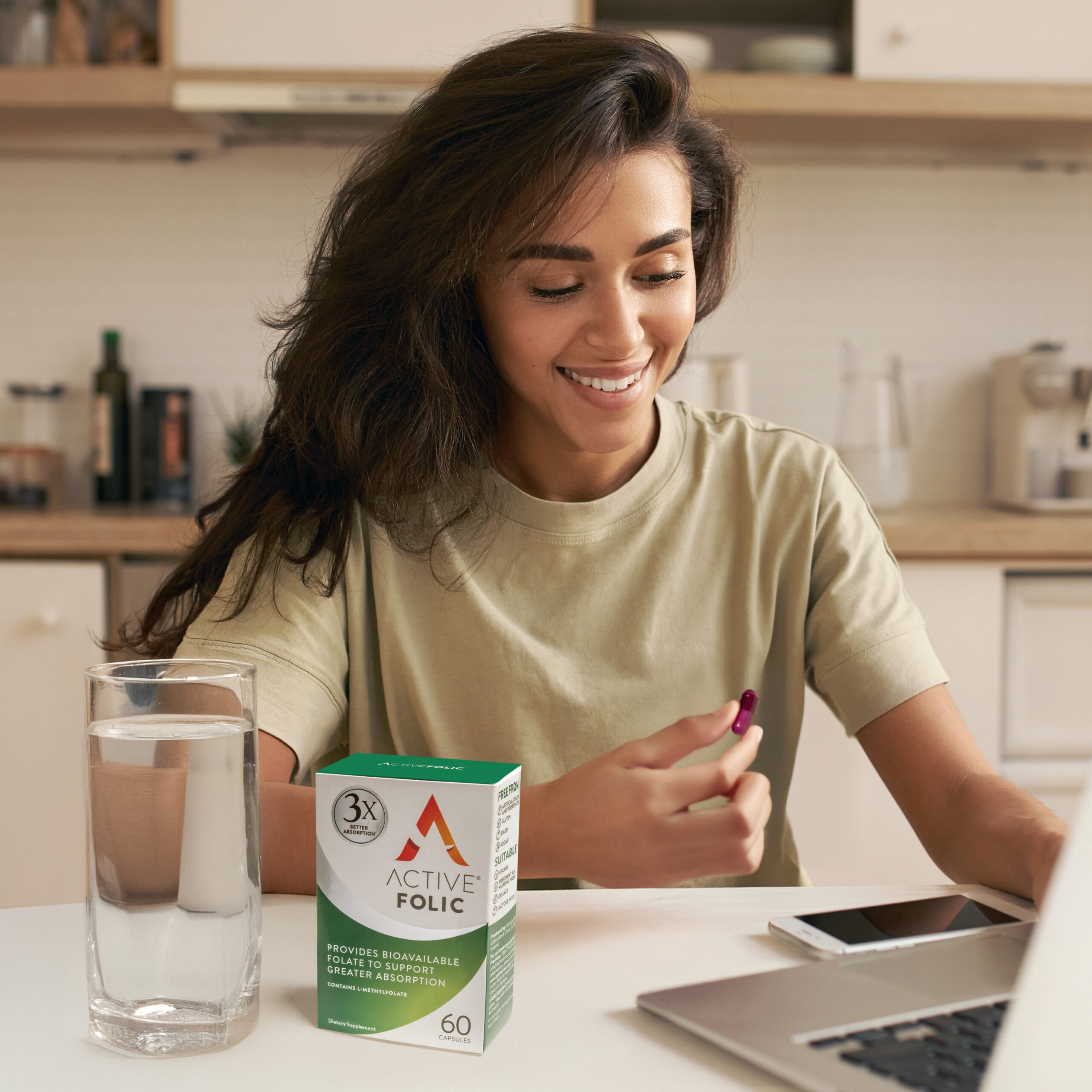 Nutrition, healthy lifestyle and body hacking. Joyful young woman nutritionist sitting in front of open laptop, having online consultation, entering information about dietary supplement in her hand Pregnancy Active Iron High Potency